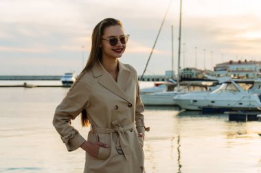 çekici bir kız gülümseyerek, onun gemi limanda bekleyen güneş gözlüğü takıyor kalın uzun saçlı