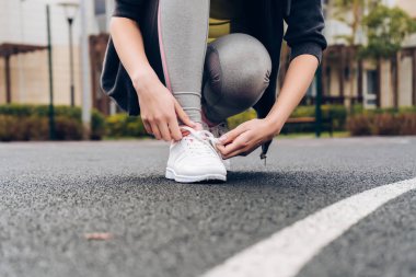 Kız onun ayakkabı bağcığı kadar üzerinde spor ayakkabılarını bağlar, uzaktan çalıştırmak hazırlar