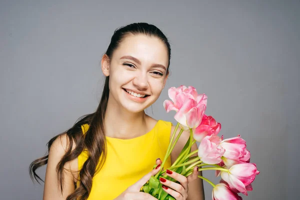 Привлекательная смеющаяся девушка наслаждается весной и праздниками, в ее руках букет ароматных цветов — стоковое фото