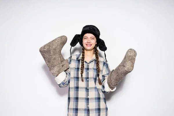 Alegre joven rusa chica con coletas sostiene gris fieltro botas, bailes y sonrisas — Foto de Stock
