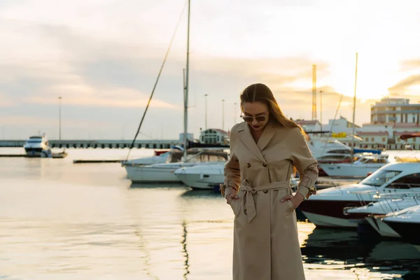 Elegante giovane donna in un elegante cappotto beige è in attesa per il suo yacht, vacanza estiva — Foto Stock