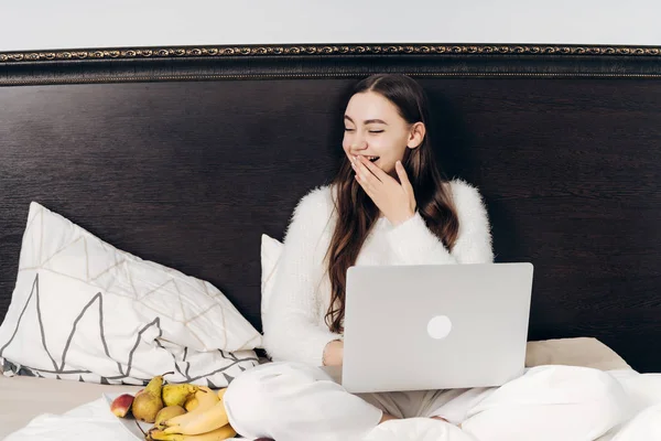 Schattig jong meisje zitten in bed, rust, kijken naar Tv-serie op laptop — Stockfoto