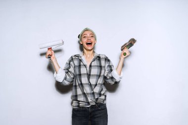 holding bir boya fırçası ve silindir boyama için onun yeni evinde tamir yaparken mutlu genç kız