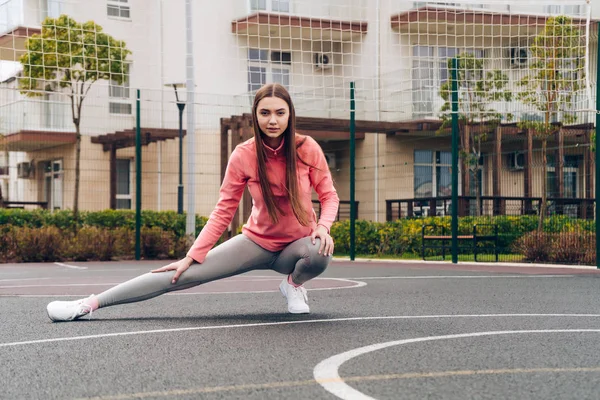 Активная стройная девочка замесить мышцы перед тренировкой на спортивной площадке — стоковое фото