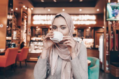 Türban Arap genç kadında şirin kafe, iyi bir ruh hali kokulu çay içer