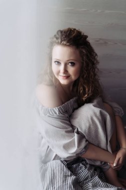 çok güzel bir elbise kıvırcık çekici genç kadın oturur, gülümseyerek ve dinlenme