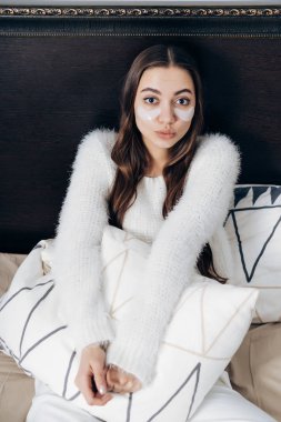 Sabahın erken saatlerinde, beyaz lekeler gözleri altında bir kız beyaz pijamalı uyandım