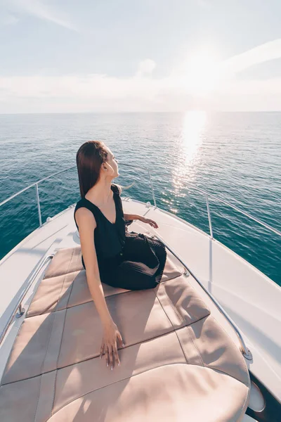 Роскошная стильная девушка в черной одежде отдыхает на своей белой яхте, наслаждается отдыхом на море — стоковое фото