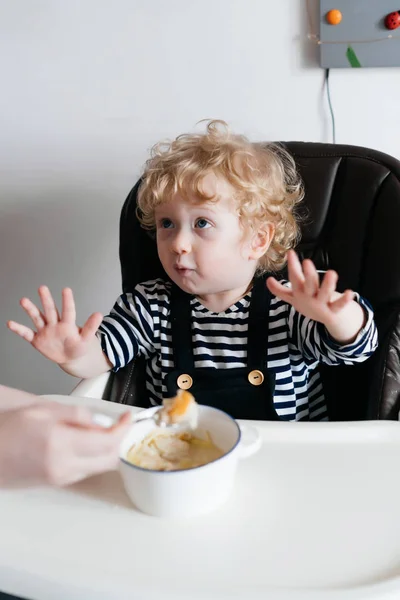 Кудрявый блондин маленький мальчик ест вкусный суп, вместе с мамой — стоковое фото