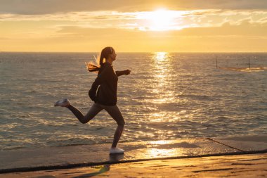 deniz kenarında günbatımında jogging, yarışmalar için hazırlanıyor emin hızlı kız