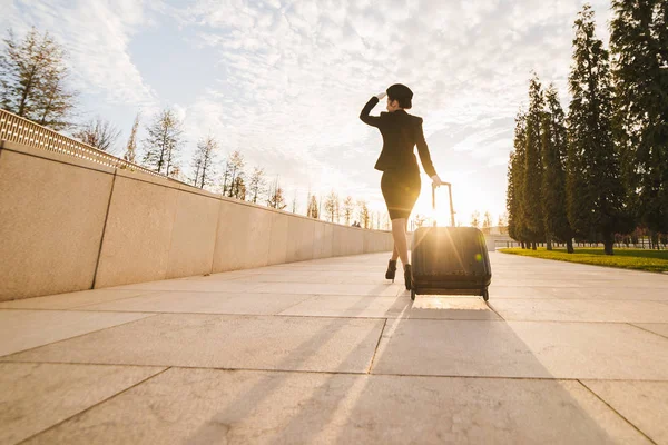 Slender young female flight attendant in uniform with a suitcase goes on her flight — Stock Photo, Image