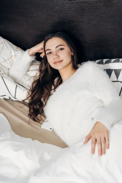 Junges hübsches Mädchen wacht frühmorgens auf, liegt in ihrem Bett, zu Hause und lächelt — Stockfoto