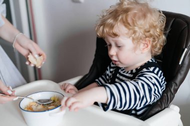 Anne küçük sarışın çocuğunu bir oğul mutfakta sıcak lezzetli püresi ile beslemeleri