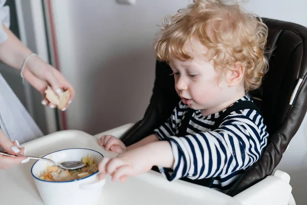 Anne küçük sarışın çocuğunu bir oğul mutfakta sıcak lezzetli püresi ile beslemeleri