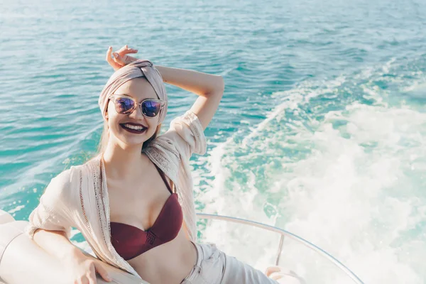 Una hermosa chica sonriente en gafas de sol disfruta de viaje por el mar, velas en el mar —  Fotos de Stock