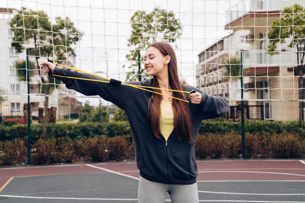 活跃的长发女孩做运动的手在运动场上的肌肉 — 图库照片