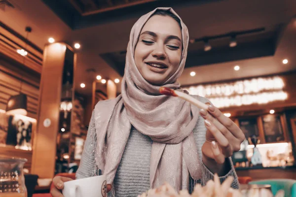 Gyönyörű Arab lány, a fejkendő a fején finom étkezés egy étteremben, jó hangulat, mosolygó — Stock Fotó
