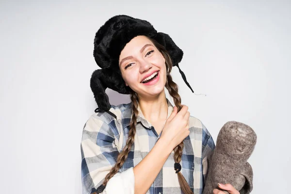 Mooie vrolijke Russisch meisje met pigtails genieten van de winter, in een warme bont muts — Stockfoto