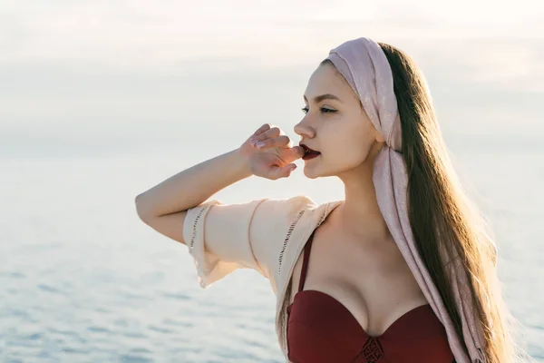 Confident attractive girl with a headscarf on her head enjoys sea voyage, posing — Stock Photo, Image