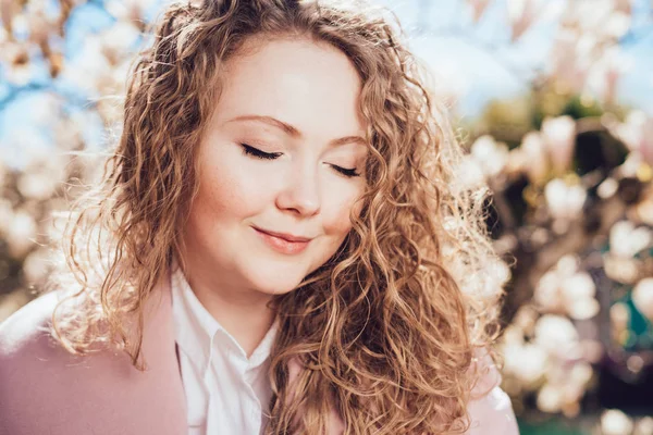 Lovely curly-haired woman smiling, closing her eyes, enjoying the warm spring weather and the sun — Stock Photo, Image