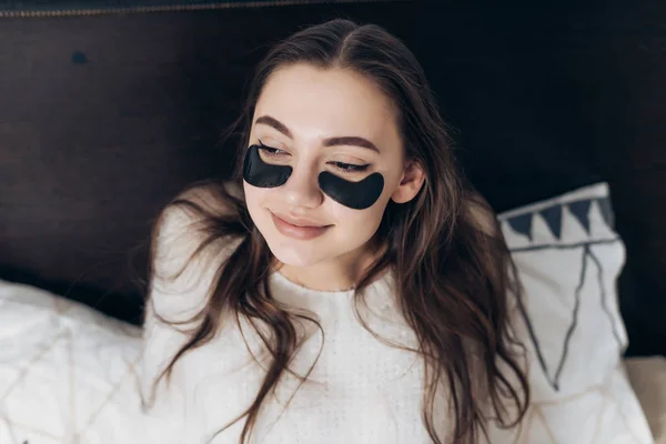 Ein junges schläfriges Mädchen mit langen Haaren wachte frühmorgens in ihrem Bett auf, unter den Augen schwarzer Flecken — Stockfoto