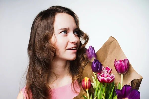 Glad tjej med långt hår håller en bukett av doftande blommor, våren semester — Stockfoto