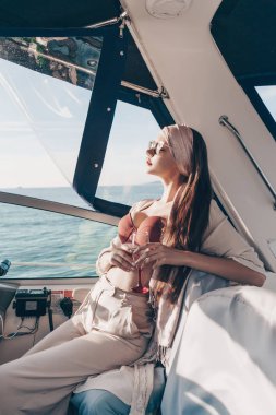 güneş gözlüğü İçecek şampanya, zengin bir şık kız bir tatil bir yatta sahiptir