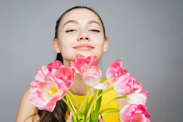 Encantadora hermosa chica disfrutando de la primavera, sosteniendo un ramo de flores rosadas fragantes — Foto de Stock