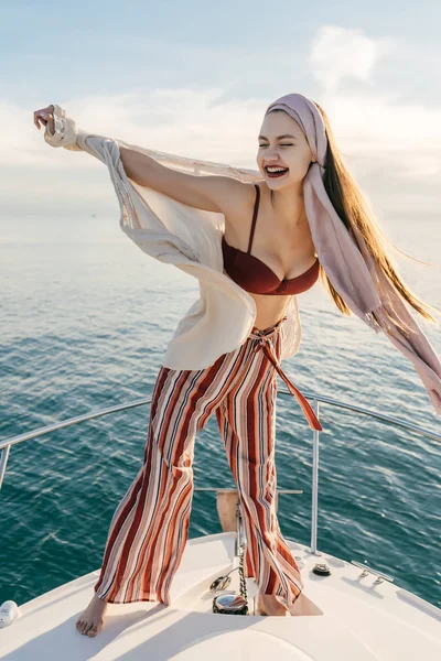 Una joven de lujo en ropa elegante de verano descansa en su yate, disfruta del viaje por el mar —  Fotos de Stock