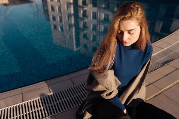 Aantrekkelijke blonde meisje genieten van ontspannen bij het blauwe zwembad in de zon — Stockfoto