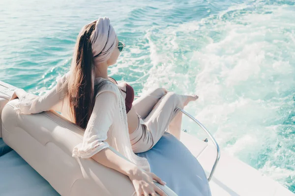 Роскошная женщина с платком на голове расслабляется на яхте, наслаждается богатой жизнью и морским путешествием — стоковое фото