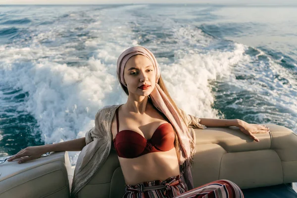 Luxusní štíhlá dívka v plavkách odpočívá a relaxuje na své jachtě, plave podél modré nekonečné moře při západu slunce — Stock fotografie