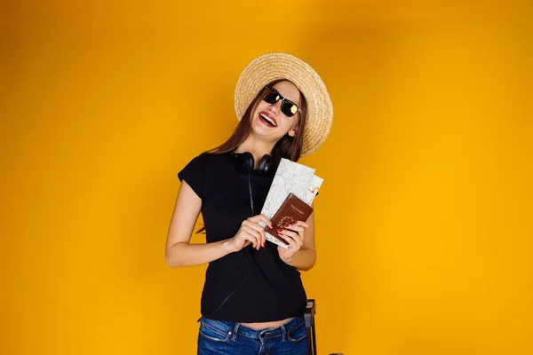 Menina de cabelos longos feliz em um chapéu e óculos de sol vai em uma viagem ao redor do mundo detém um passaporte em mãos — Fotografia de Stock