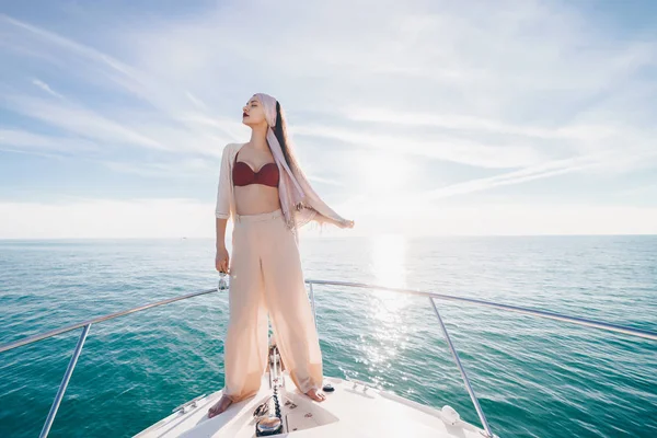 Una chica de lujo en ropa de verano con estilo se encuentra en un yate al sol, se relaja y relaja —  Fotos de Stock