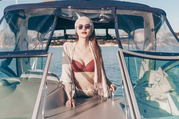 Una chica sexy de lujo en gafas de sol negras disfruta de unas vacaciones en un yate, navega en el mar Caribe —  Fotos de Stock