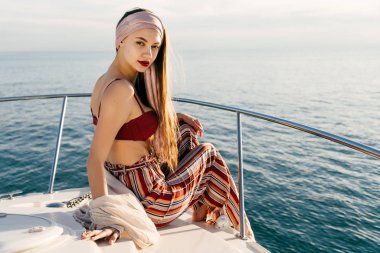 dinlenme şık yazlık giysiler ve güneş bir yatta rahatlatıcı, poz kendine güvenen genç kadın