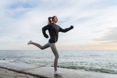 spor gri emin hızlı kız akşam, Denizi çevresinde çalışan giyim kulaklıklar müzik dinlemek