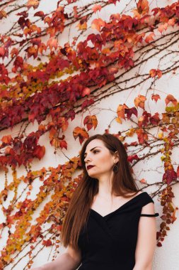 kalın saç onun bahçesinde duvara poz ile zarif genç kadın hakkında bir şey düşünüyor