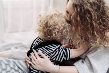 kıvırcık saçlı iyi huylu anne sarılma onun genç oğlu, dostu aile
