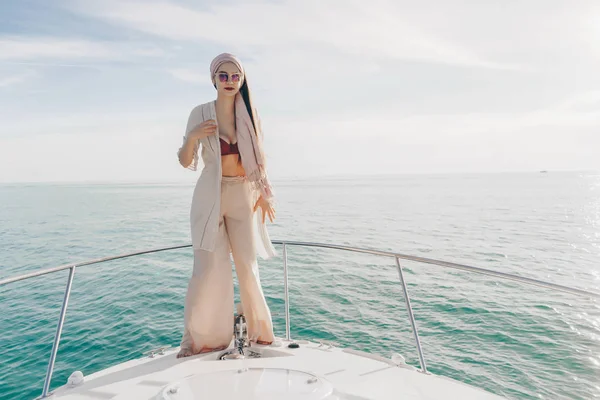 一个穿着夏装的豪华时尚女孩站在游艇上, 享受着温暖的夏日风和阳光。 — 图库照片