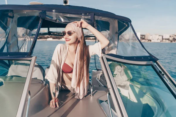 Glückliche junge Frau mit Sonnenbrille genießt ein reiches Leben und Urlaub auf einer Jacht — Stockfoto