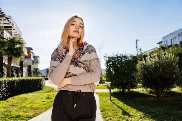 Confiante menina loira com um lenço em seus ombros posando nos raios do sol da primavera — Fotografia de Stock