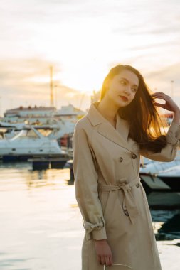 onun yat günbatımında dinlenme seaport adlı bekleyen bej bir palto güzel genç kadın