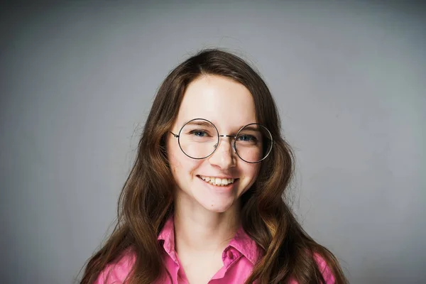 Heureuse jeune femme employée de bureau en chemise rose et lunettes souriantes et regardant la caméra — Photo