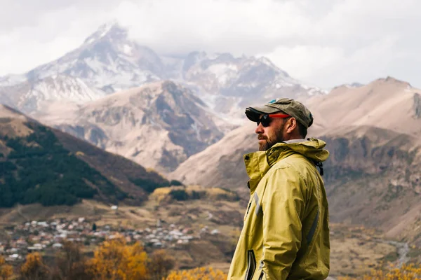 Взрослый бородатый мужчина в теплой куртке наслаждаясь горной природой и пейзажем — стоковое фото