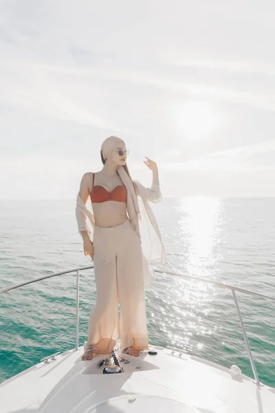 Menina bonita de luxo em roupas de verão elegantes desfrutando de uma viagem marítima, posando contra o mar — Fotografia de Stock