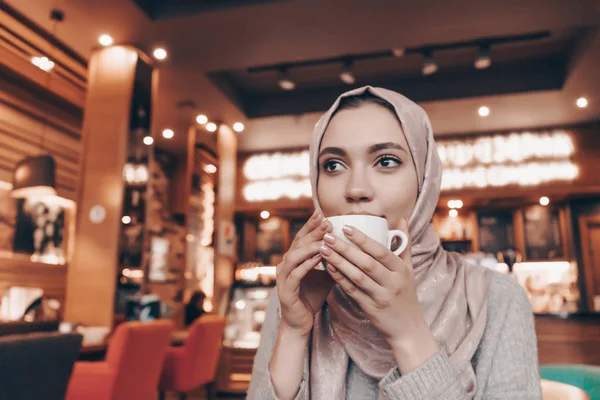 Bájos Arab lány hidzsáb italok aromás kávét egy étteremben — Stock Fotó