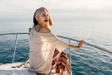 mutlu şık kız beyaz bir yatta oturur, Karayip Denizi üzerinde günbatımında yelken