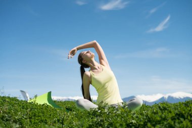 Yoga yaparken güneş, yeşil çim üzerinde bir parkta meditasyon ince esnek kız