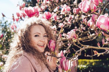 sıcaklık ve bahar çiçek, bir arka plan karşı parkta poz kıvırcık saçlı gülen kadın seviyor